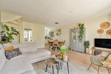 A bright and modern living room featuring a cozy sofa, stylish decor, and abundant greenery, creating a welcoming and serene atmosphere.