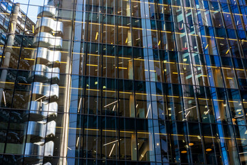 Glass curtain walls of office towers with warm interior lighting, suggesting activity, enterprise and collaboration.