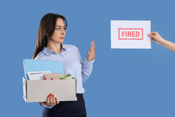 Businesswoman rejecting paper with word FIRED from hand on blue background