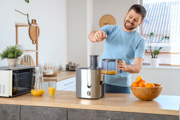 Young man making orange juice in kitchen