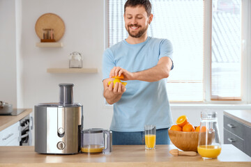 Young man with modern juicer in kitchen