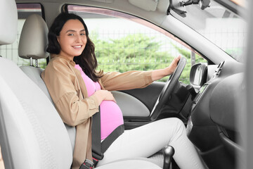 Young pregnant woman with seat belt sitting in car