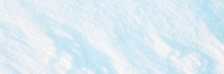 Wide panoramic winter background with snowy ground. Natural snow texture. Wind sculpted patterns on snow surface.