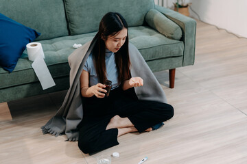 woman sitting on sofa covered with blanket freezing blowing running nose got fever caught cold,...