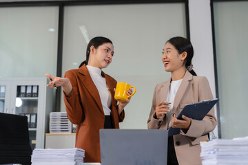 female colleague Asian descent holds a cup of coffee and talking discussion ideas and happily.