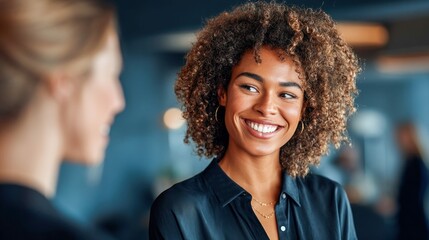 Fototapeta premium A beautiful, smiling woman with curly hair enjoys a conversation with a colleague.