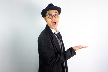 pria asia berpakaian mafia memakai kacamata dan topi, membuat gerakan tangan menunjukan produk...
