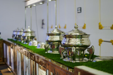 A buffet setup with shiny steel food warmers arranged on a decorated counter at a wedding or event.