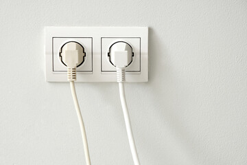 Socket with plugs on light wall, closeup