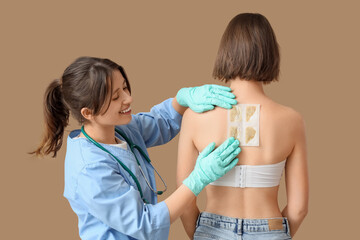 Female doctor applying mustard plaster on patient's back against brown background