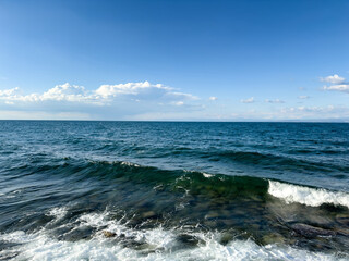 strong sea wave breaking over coastal rocks on a bright sunny day. dynamic sea scene with energy and natural force