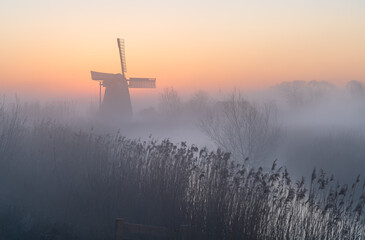 Dawn at a traditional, Dutch windmill in the spring fog.