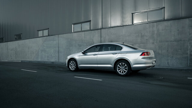 Silver Volkswagen Passat parked near warehouse. Side view of german sedan near grey concrete wall. Kyiv, Ukraine - August 05 2015.