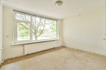 A vacant room featuring a large window that offers a clear view of green trees outside, showcasing natural light and a minimalistic design.