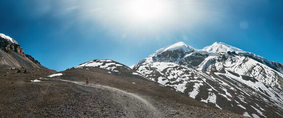 Scenic panoramic view of snowy mountains and lonely of hiker with walking along mountain path.. Himalayas, Nepal.