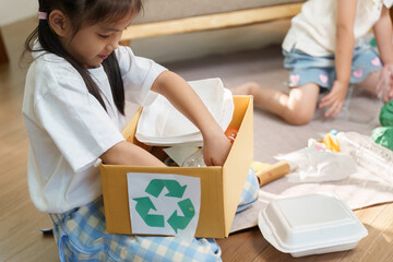 Recycling and Sustainability. A little girl eagerly sorting recyclable materials into a designated...