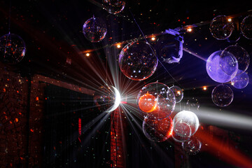 Disco balls hang from the ceiling, reflecting vibrant lights at a night club party. A lively and energetic atmosphere for dancing and celebration.