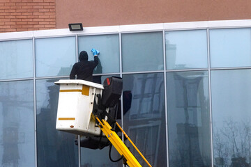 A window washer washes the windows of an office building, a skyscraper.