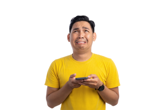 Worried young Asian man holding mobile phone and looking up with sad expression isolated on transparent background