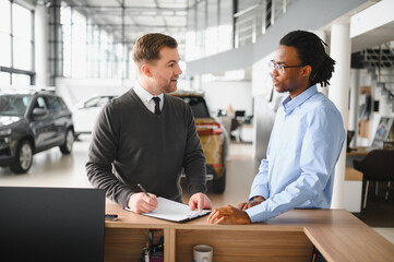 A consultant at a car dealership helps a customer choose a new car