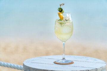 Elegant gin and tonic cocktail served in a wine glass, garnished with cucumber ribbon and orange...