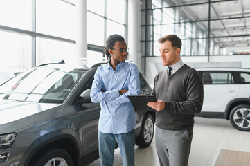 A consultant at a car dealership helps a customer choose a new car