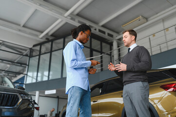 A consultant at a car dealership helps a customer choose a new car