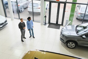 Fototapeta premium Portrait of male client talking to professional car dealer in dealership.