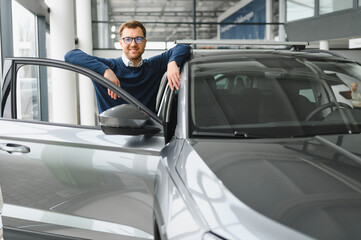 I got a new car today. Portrait of a happy mature man smiling posing near his new car at the local...