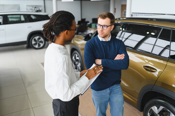 Naklejka premium Portrait of male client talking to professional car dealer in dealership.