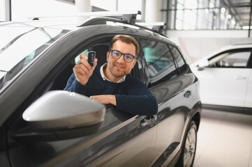 Young man is choosing a new vehicle in car dealership