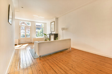 A bright, spacious living area with natural light pouring in, featuring wooden floors and a simple, elegant sofa that complements the minimalist aesthetic.