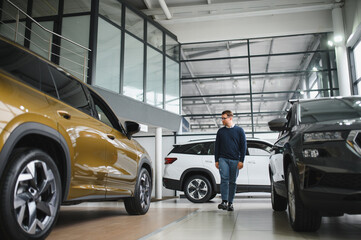 Young man is choosing a new vehicle in car dealership