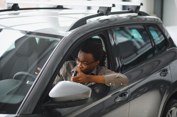 Young african american man is choosing a new vehicle in car dealership