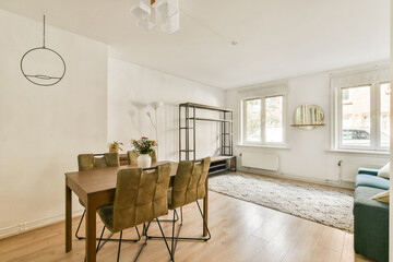 A contemporary living space featuring a dining table, comfortable seating, and large windows that offer natural light, creating a cozy atmosphere.