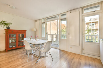 Bright and inviting dining area featuring a modern table and chairs, alongside stylish storage and large windows for natural light.