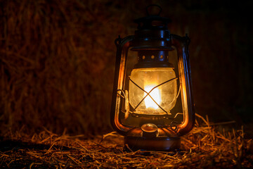 antique kerosene lamp with lights on a haystack in a barn at night