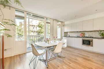 A stylish kitchen with a dining area featuring large windows that bring in natural light, creating a welcoming and airy atmosphere perfect for meals.