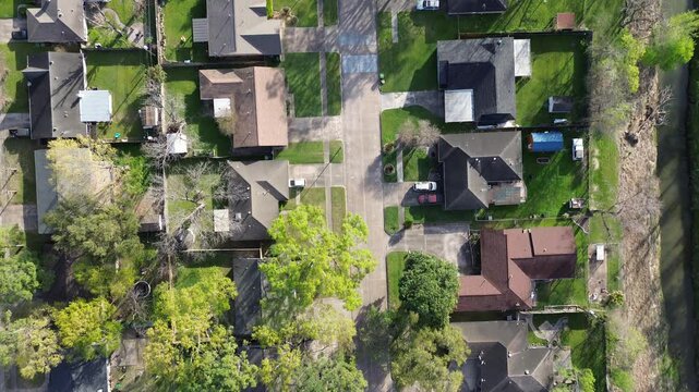 Suburban residential houses along Cole Creek grass-lined channel in Fairbanks Northwest Crossing neighborhood, Harris County, greater Houston area, early morning spring, detached homes, flyover