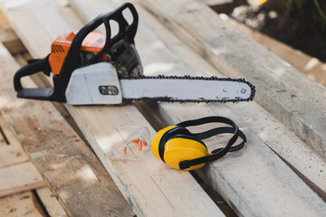 A chainsaw and safety goggles are on a wooden surface