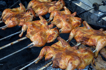 Chicken on the fire. Chicken BBQ. Roasted chicken in the oven in a restaurant, closeup of photo. Grilled chicken on the spit in the smoke. Fast food
