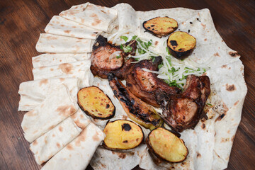 Grilled meat. Pork barbecue. Fried meat with onions, potatoes wrapped in pita bread. Lamb steak on pita bread with grilled potatoes on wooden table. Restaurant food. Fast food