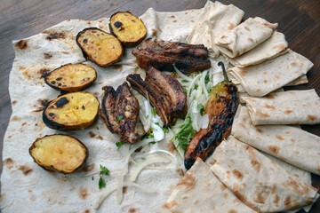 Grilled lamb ribs with grilled potatoes and herbs on pita bread. Pork barbecue. Potato bbq. Fried lamb on a table. Fast food. Restaurant food