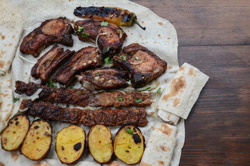 Barbecue with grilled meat and shish kebab. Grilled lamb ribs, kebab, potatoes and pita bread on wooden board. Restaurant food, pork barbecue, bbq.