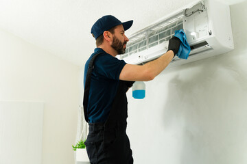 Technician cleaning air conditioner filter with detergent and rag