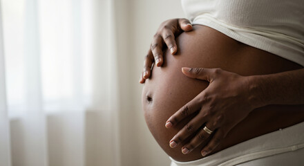 A pregnant woman tenderly hugs her belly on a gray background. The concept of preparing women for pregnancy, childbirth, motherhood.