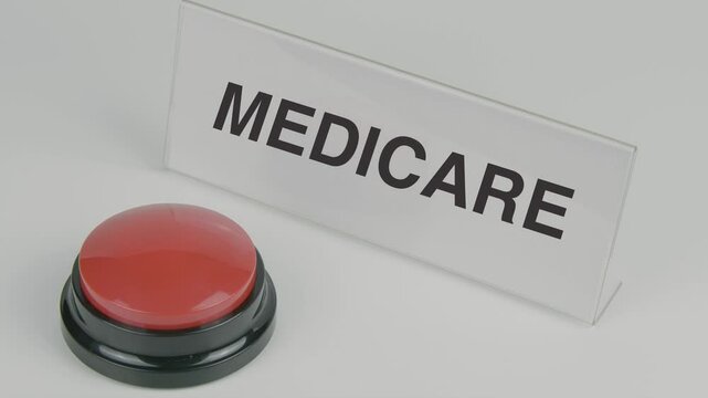 "Medicare" text or word displayed on a nameplate as a hand presses a red button, set against a white background, symbolizing healthcare coverage, insurance, and support for individuals, especially sen