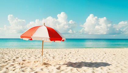 Red and white beach umbrella casting shadow on sandy shore  