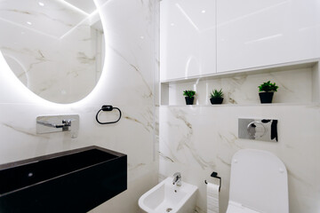A bathroom featuring a toilet, sink, and a mirror for grooming purposes