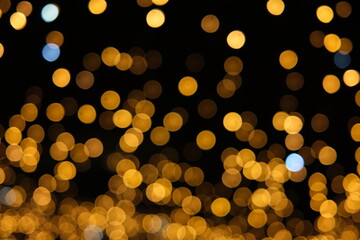 Golden bokeh lights on black background &mdash; ideal for abstract, elegant, and festive designs with radiant, decorative flair. Perfect for celebrations and artistic visuals.